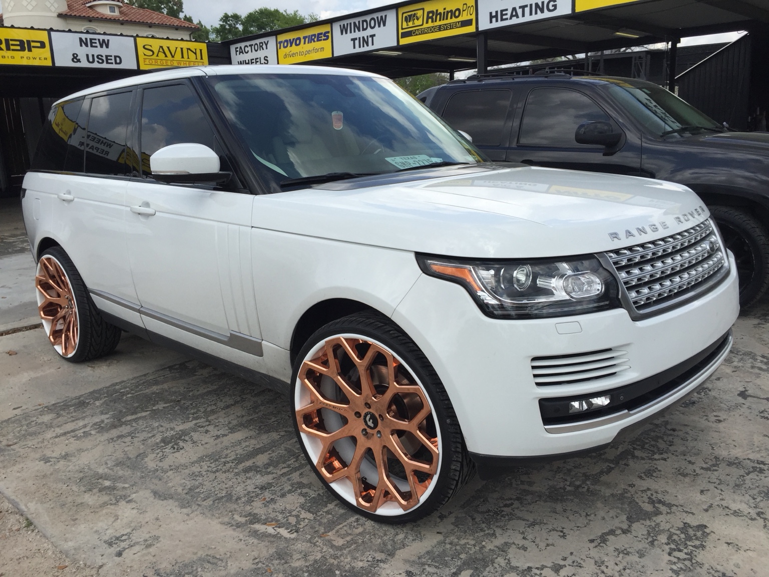 White Range Rover with oversized copper-toned custom wheels.