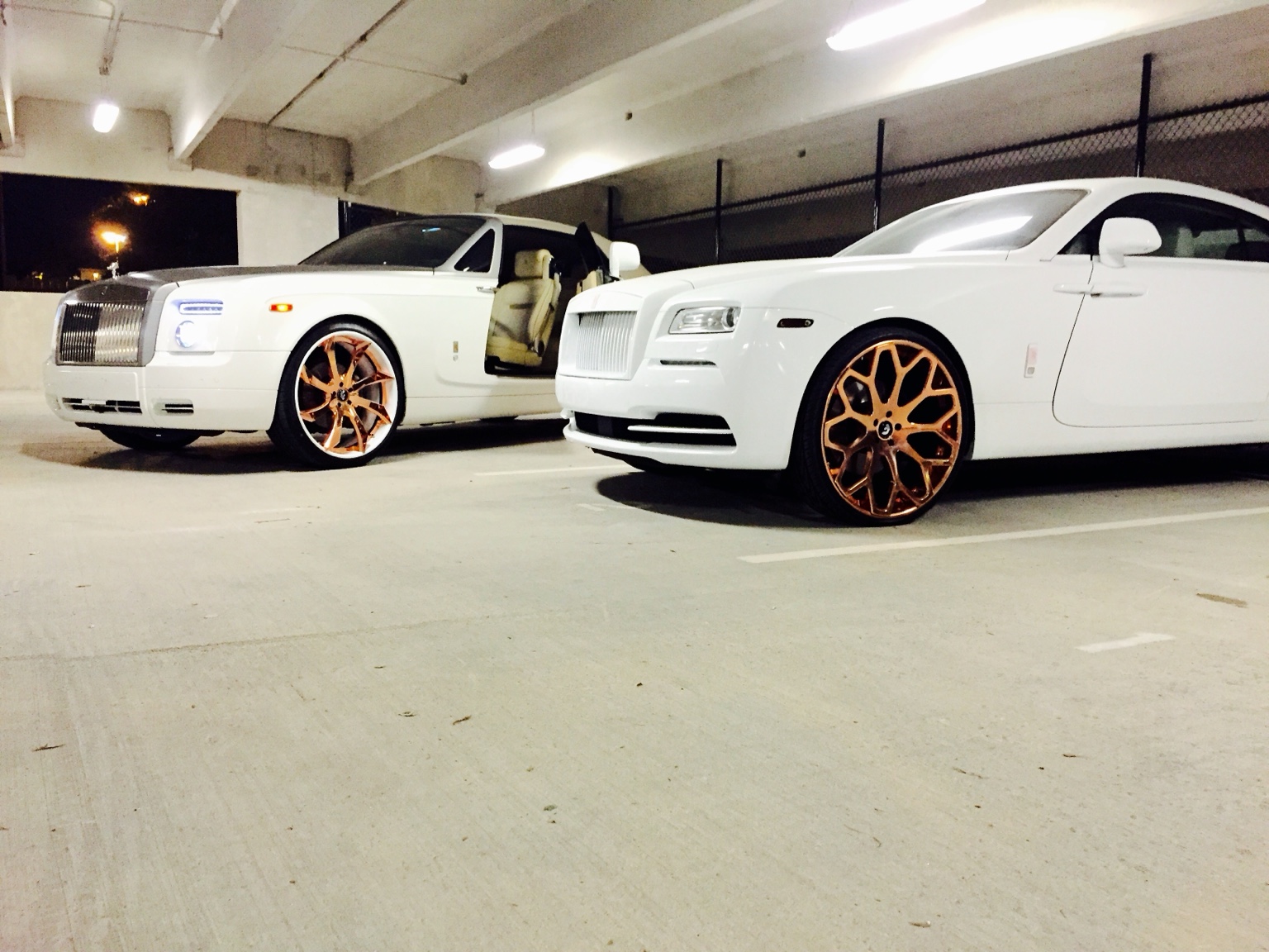 Two customized white Rolls-Royce vehicles together.