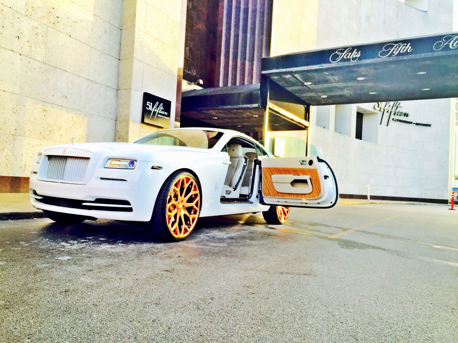White Rolls-Royce with distinctive wheel finish.