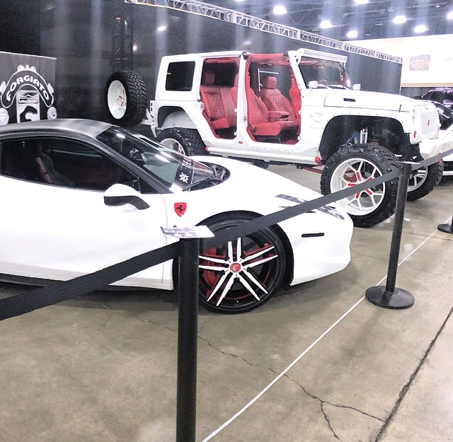 White customized Jeep and sports car at an automotive exhibition.